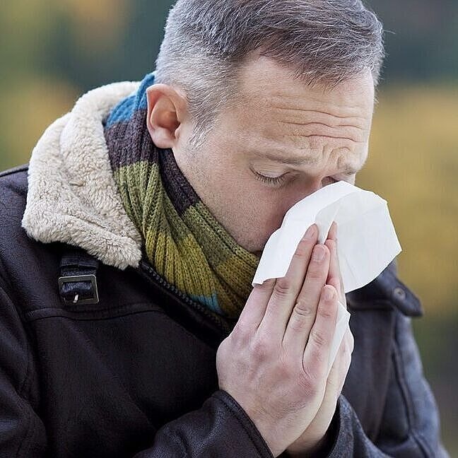 Mann schnäuzt in ein Taschentuch