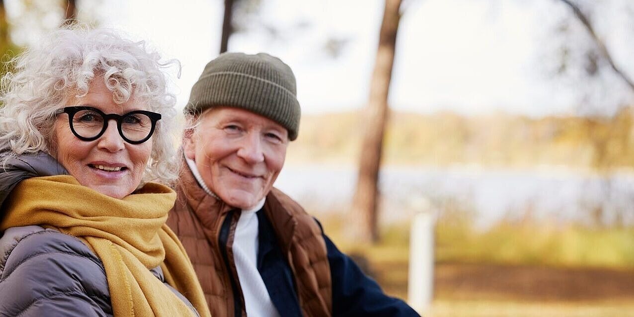Älteres Paar sitzt in einer herbstlichen Landschaft