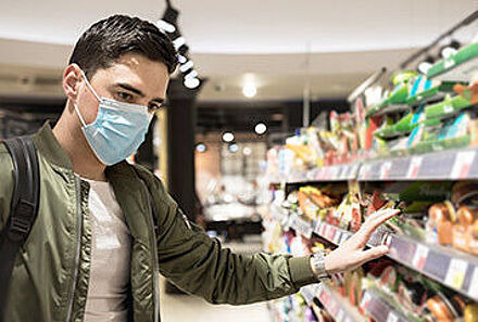 Mann trägt eine Mund-Nasen-Bedeckung beim Einkaufen im Supermarkt