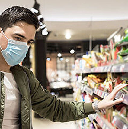 Mann trägt eine Mund-Nasen-Bedeckung beim Einkaufen im Supermarkt
