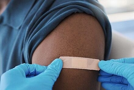 Jemand klebt ein Pflaster auf den Oberarm einer Person