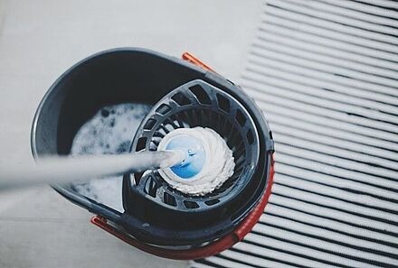 Blick von oben in einen Putzeimer mit Mopp darin