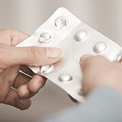 Hände die eine Tablettenpackung halten