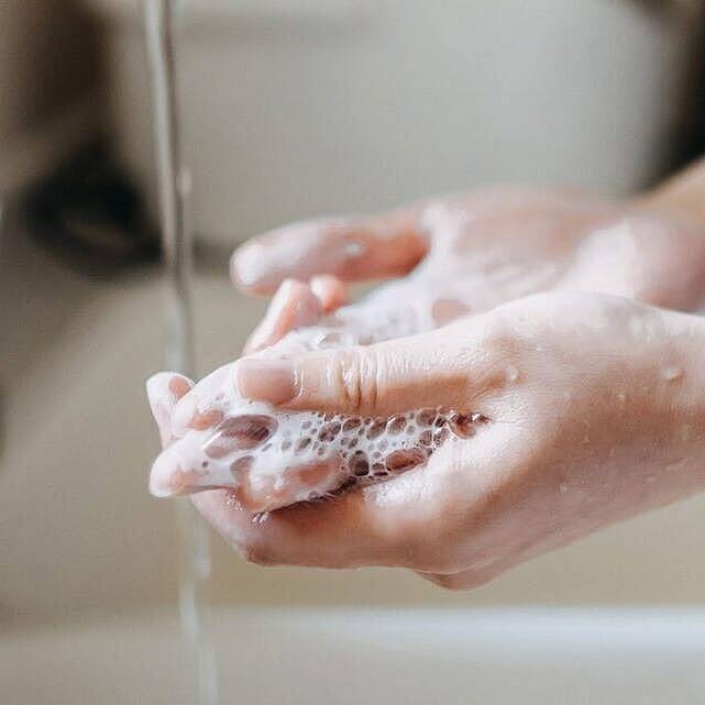 Eine Person steht am Waschbecken und wäscht sich die Hände. Man sieht nur die Händer und Arme.