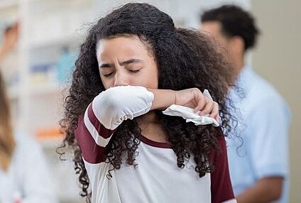 Jugendliche niest in Armbeuge