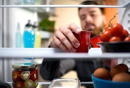 Männliche Person nimmt einen Plastikbecher aus dem Kühlschrank