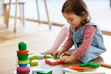 Mädchen spielt auf dem Boden mit Holzspielzeug
