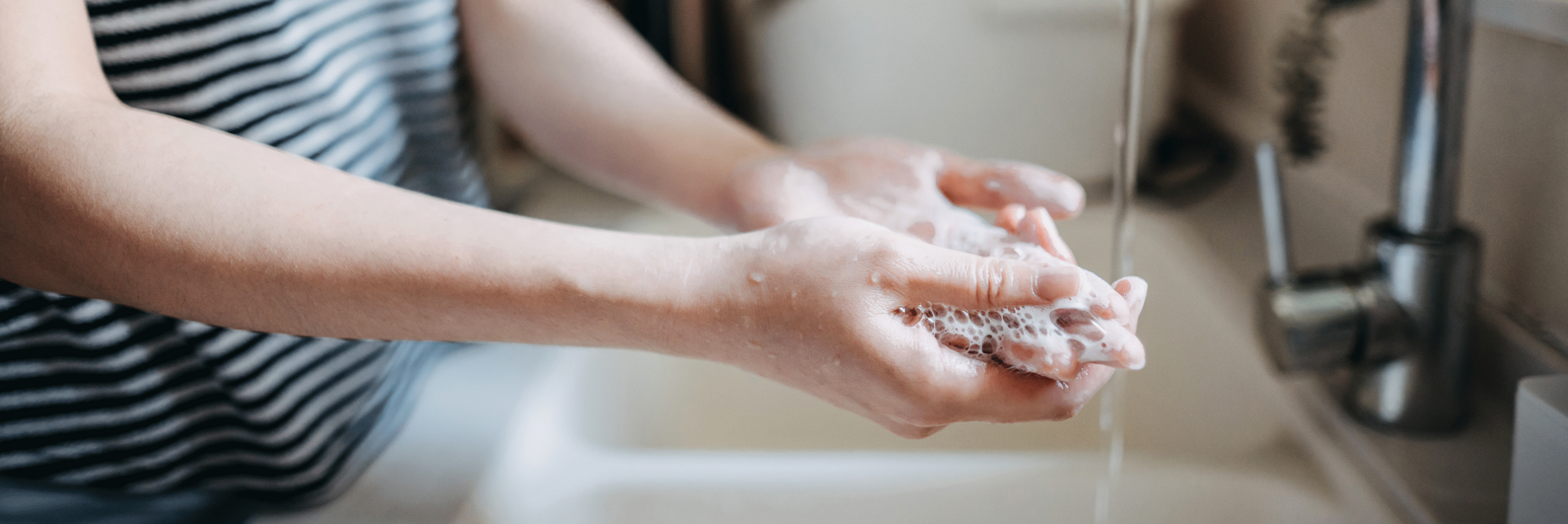 Person wäscht sich die Hände mit Seife über einem Waschbecken