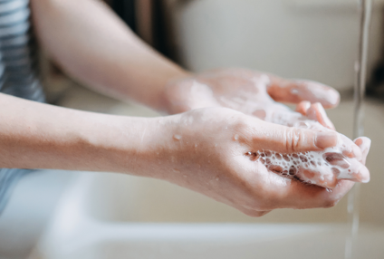 Person wäscht sich die Hände mit Seife über einem Waschbecken