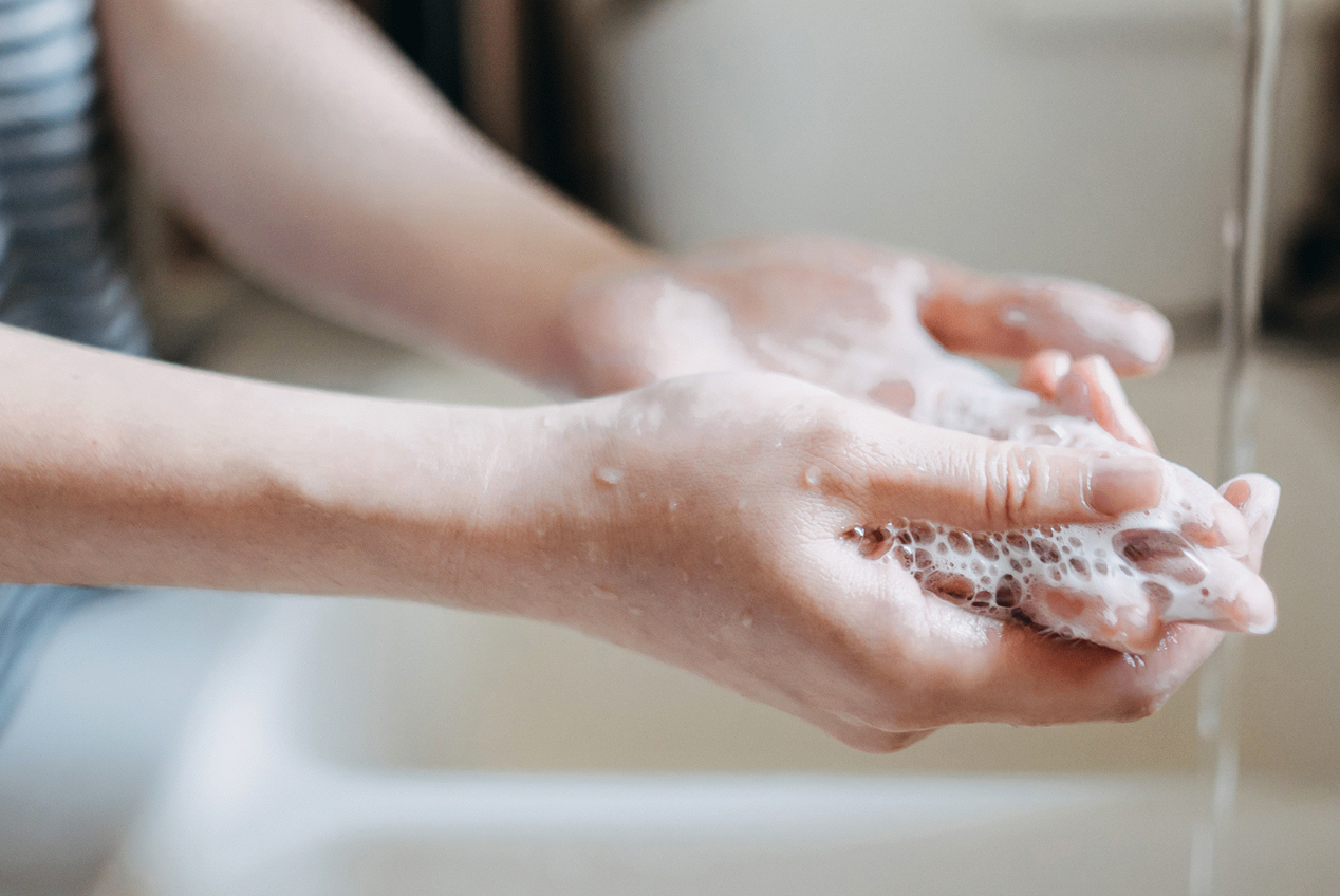 Person wäscht sich die Hände mit Seife über einem Waschbecken