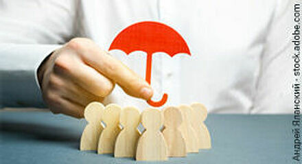 Hand hält kleinen roten Regenschirm über eine Gruppe von Holzfiguren