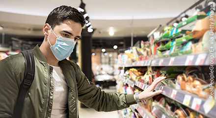 Mann trägt eine Mund-Nasen-Bedeckung beim Einkaufen im Supermarkt