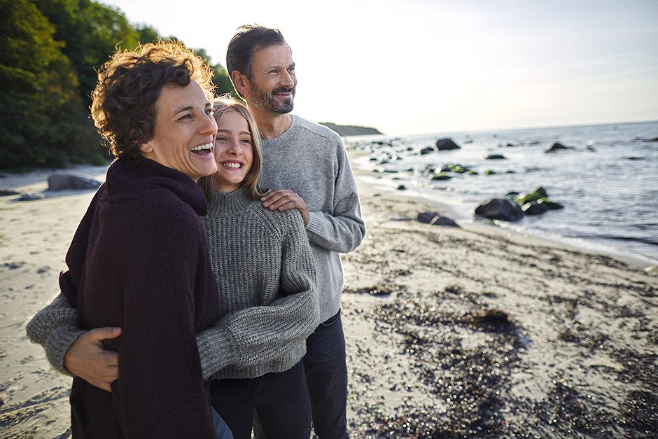 Drei Personen stehend lachend am Strand