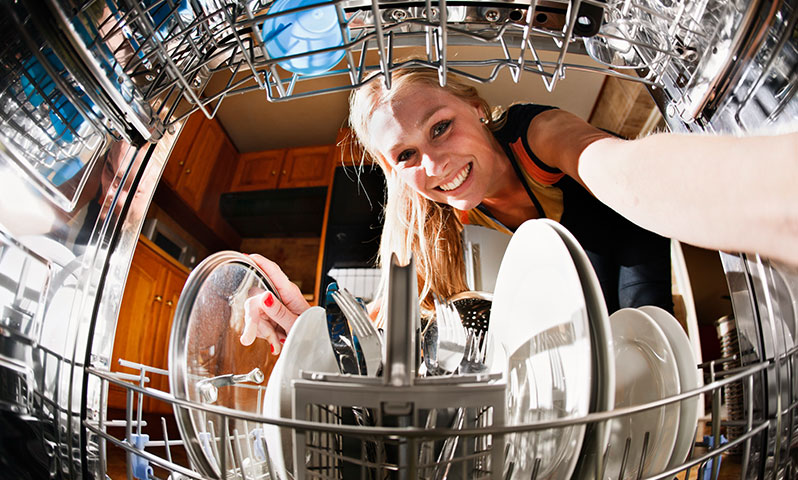 Frau räumt Geschirrspülmaschine ein (© iStock.com / RapidEye)