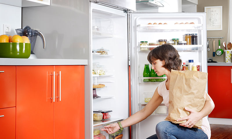 Frau räumt Kühlschrank ein (© iStock.com / JazzIRT)